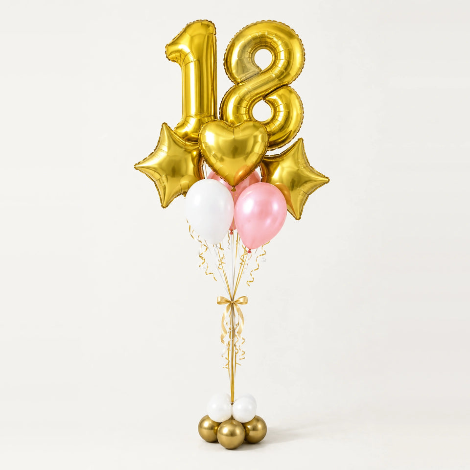 Bouquet de globos con número 18 dorado, cintas y base de globitos blancos y dorados sobre fondo claro