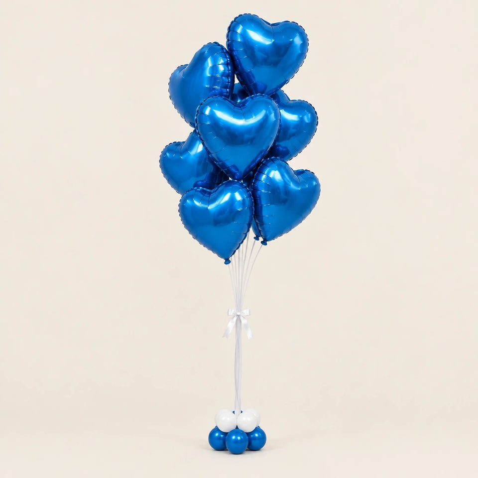 Ramo de globos de corazón azul metalizado con lazo blanco y base de globitos sobre fondo beige.