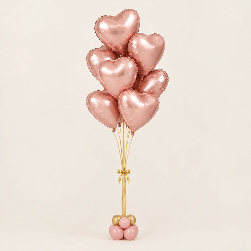 Ramo de globos de corazón oro rosa con cintas doradas y base de globitos, sobre fondo claro