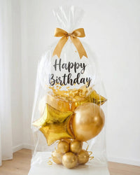 Bouquet de globos Happy Birthday dorado empacado en bolsa transparente con lazo dorado listo para entrega en Lima