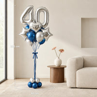 Bouquet de globos 40 plateados y azules junto a un sofá, con medidas de 200 cm de alto y 60 cm de ancho