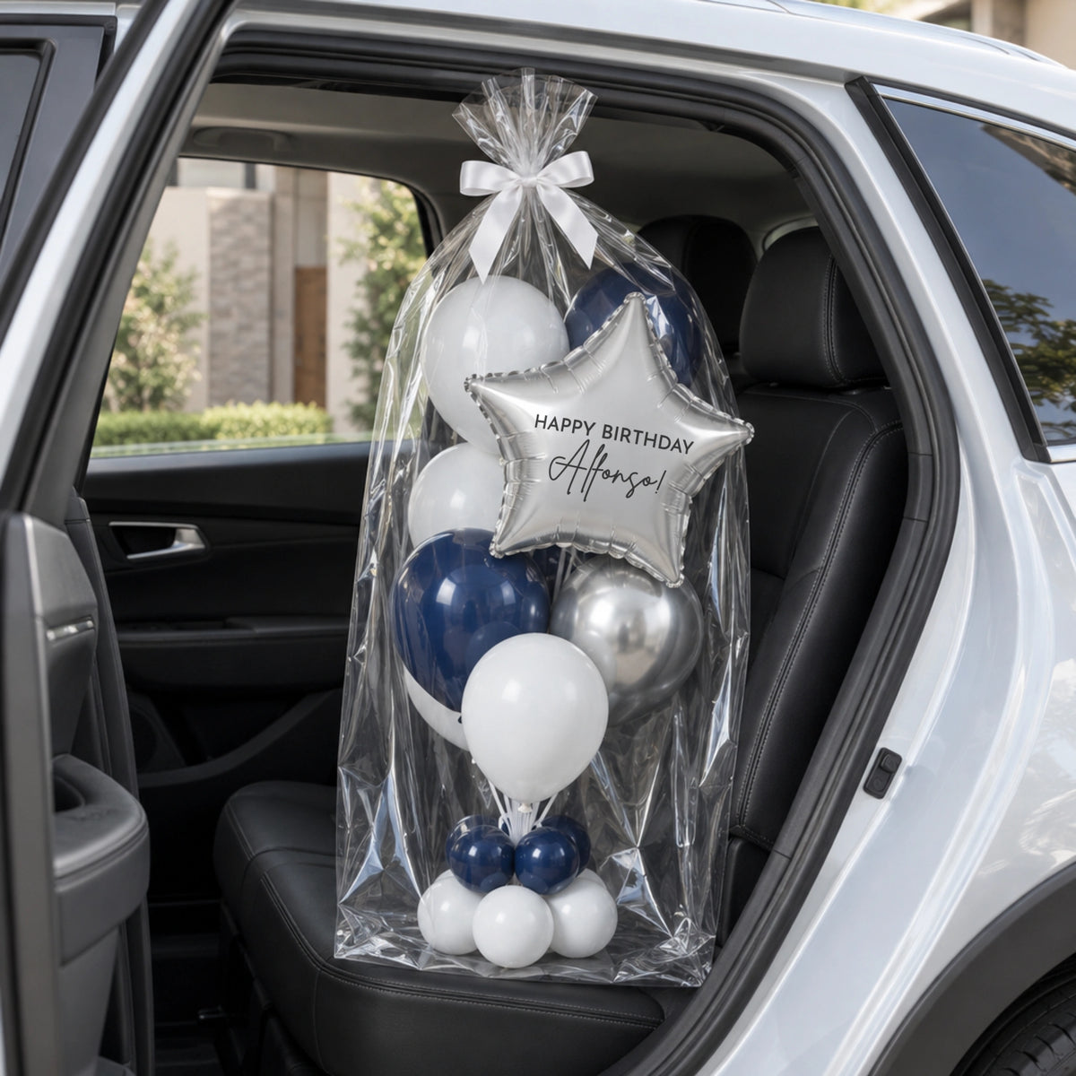 Bouquet de globos con estrella plateada, envuelto en celofán sobre el asiento trasero de un auto