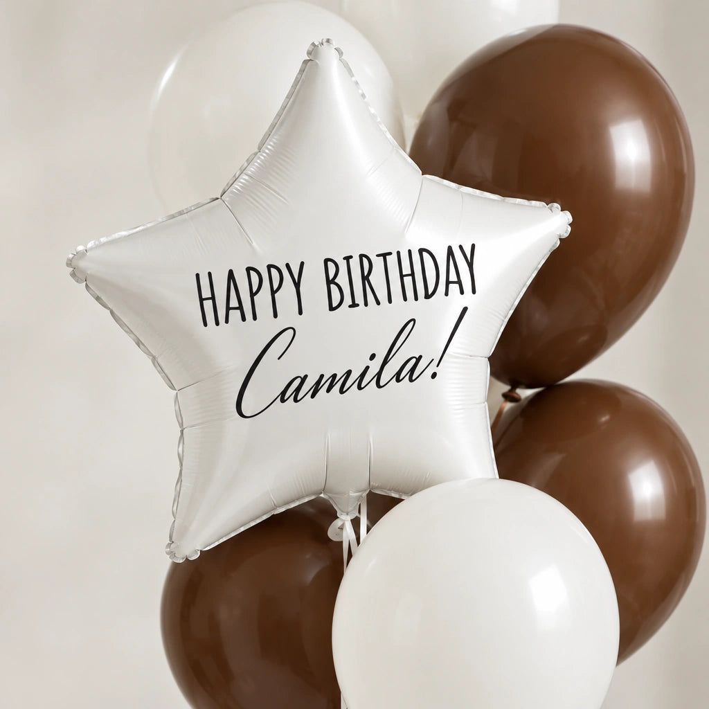 Globo de estrella blanco con la frase Happy Birthday Camila, en primer plano entre globos blancos y chocolate.