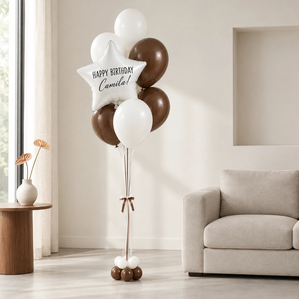 Bouquet de globos con estrella de cumpleaños junto a un sofá en una sala luminosa.