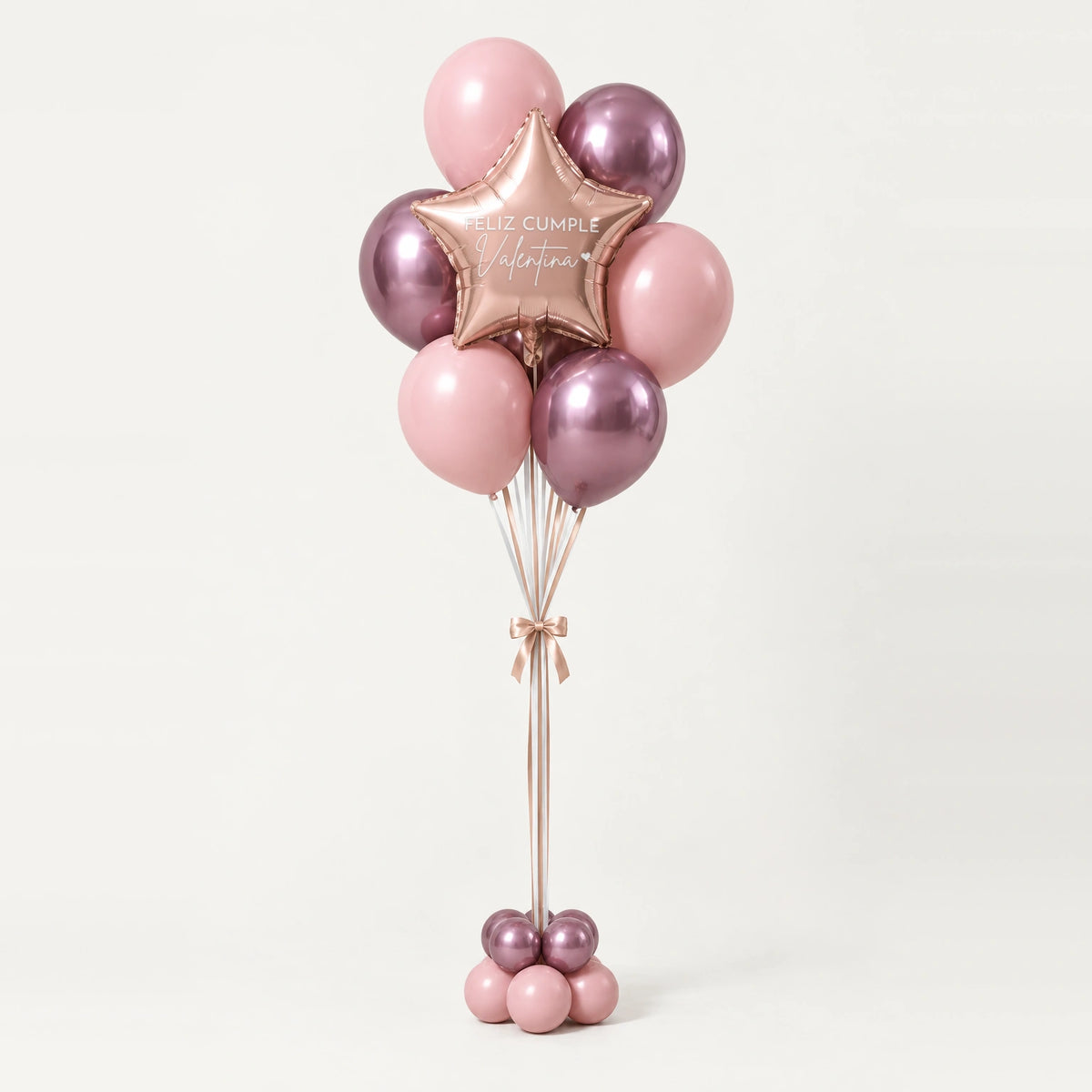 Bouquet de globos rosas con estrella oro rosa y base de globitos, sobre fondo claro.