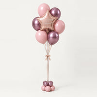 Bouquet de globos rosas con estrella oro rosa y base de globitos, sobre fondo claro.