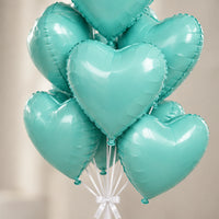 Ramo de globos de corazón aqua metalizado en primer plano, con cintas blancas