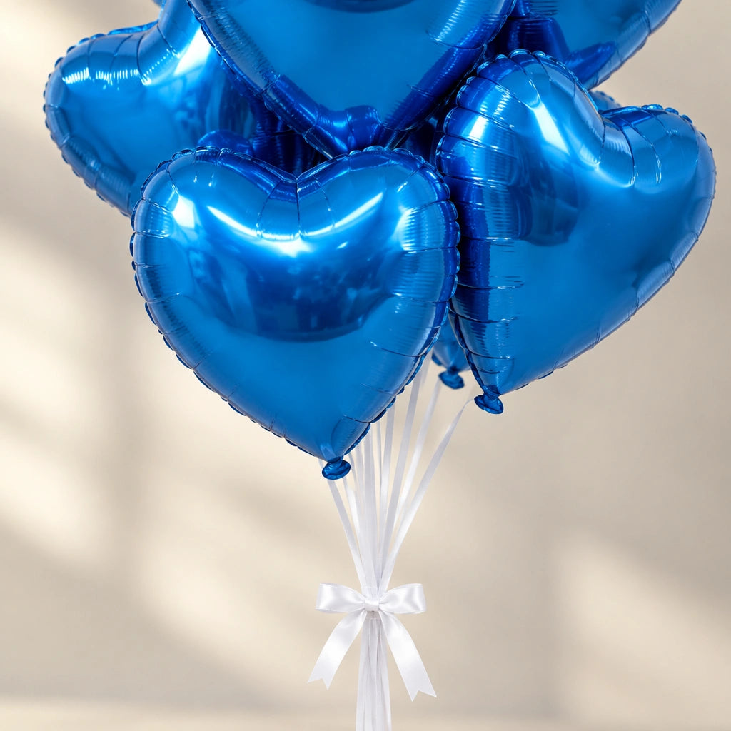 Detalle de globos de corazón azul metalizado y sus cintas blancas sujetas con un lazo.