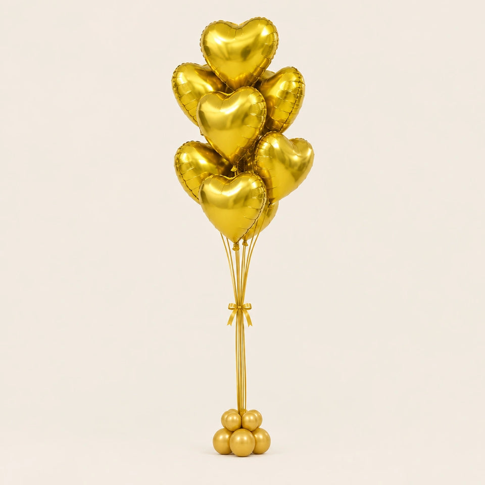Ramo de globos de corazón dorados con base de globitos, sobre fondo claro.