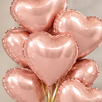 Globos de corazón oro rosa metalizado vistos de cerca, con sus reflejos y bordes sellados