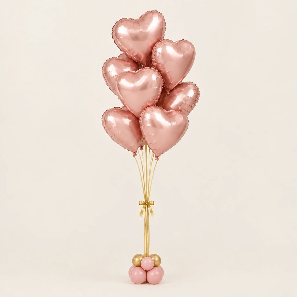 Ramo de globos de corazón oro rosa con cintas doradas y base de globitos, sobre fondo claro