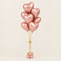 Ramo de globos de corazón oro rosa con cintas doradas y base de globitos, sobre fondo claro