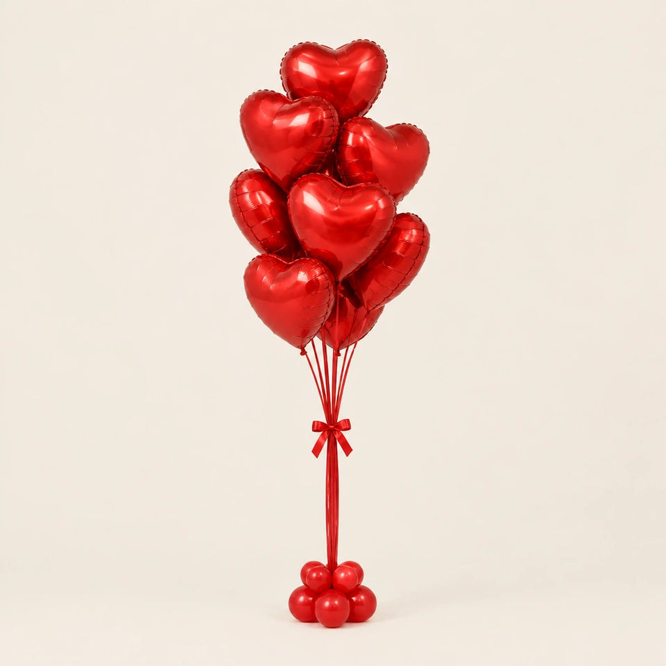 Ramo de globos de corazón rojos con lazo y base de globitos, sobre fondo claro.