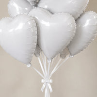 Detalle de globos de corazón blancos metalizados y cintas sujetas con un lazo