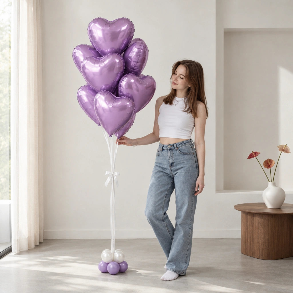 Ramo de globos de corazón lila junto a una mujer que lo sostiene y lo mira en una sala.