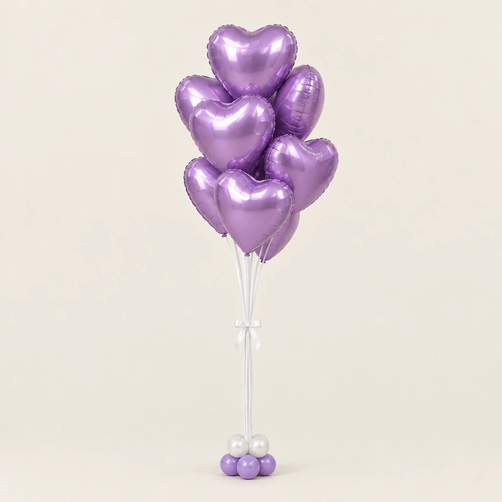 Ramo de globos de corazón lila metalizado con base de globitos y lazo blanco sobre fondo claro.