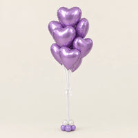 Ramo de globos de corazón lila metalizado con base de globitos y lazo blanco sobre fondo claro.